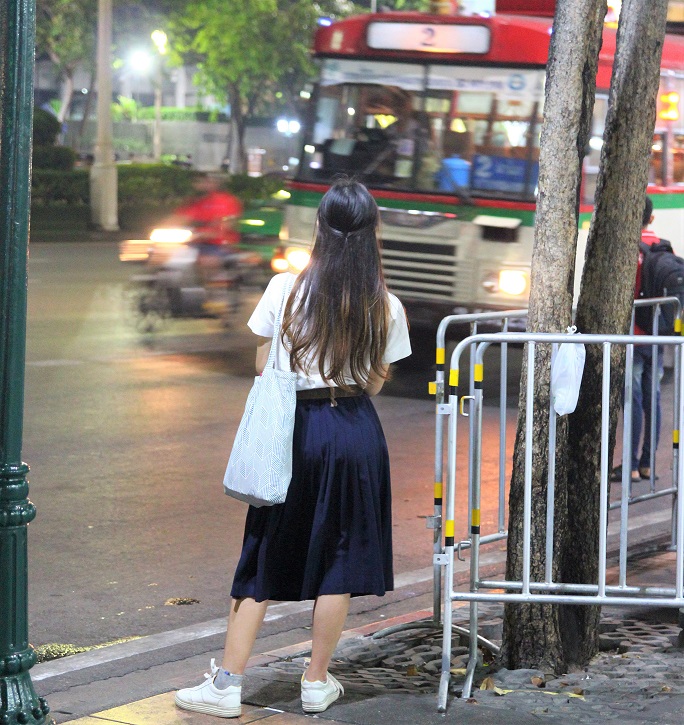 バンコクのカオサン通りでバスを待つ女子高生