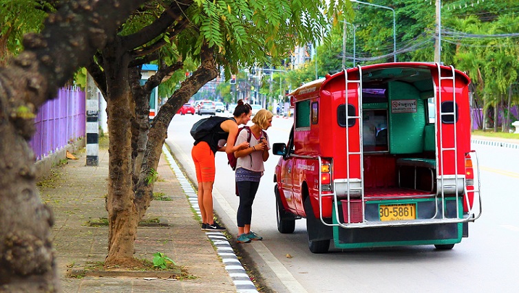 タイのチェンマイ大学前の大通りでソンテウに乗るバックパッカーの白人女性たちの写真