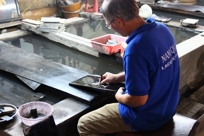 ホーチミンの螺鈿細工の工場｜水で木材と貝の表面を研磨する職人の写真｜ベトナム旅行