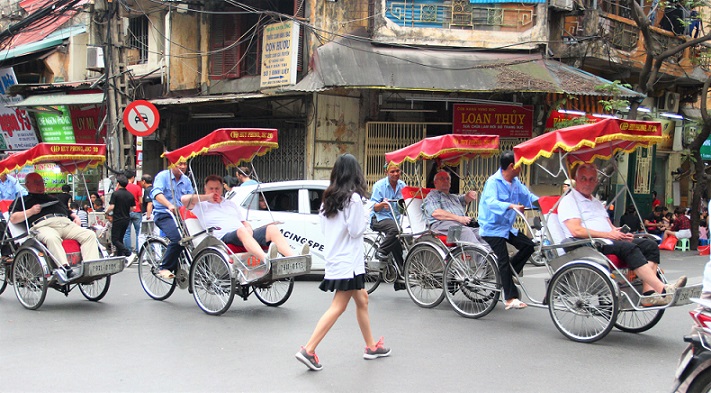 ハノイの旧市街を走るシクロをよけて歩く女性【ベトナム旅行】