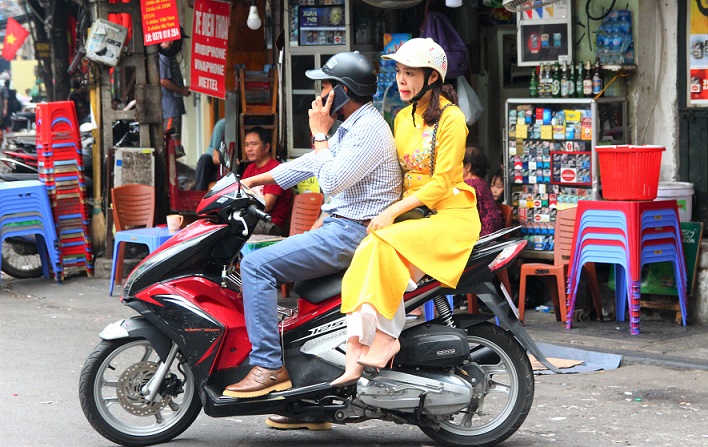 ハノイの旧市街を走るバイクに乗るアオザイを着た女性【ベトナム旅行】