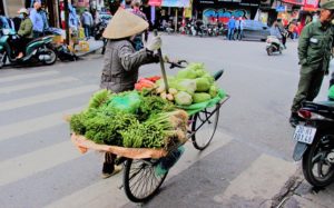ハノイの道路で野菜を昔ながらの行商をする老婆の写真