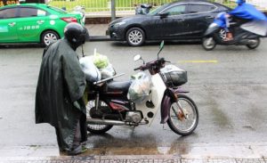 フエで買い物をした荷物をバイクに載せるベトナム男性