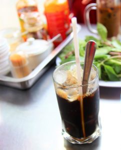 フォークインのテーブルに置かれた調味料と野菜とベトナムアイスコーヒーの写真