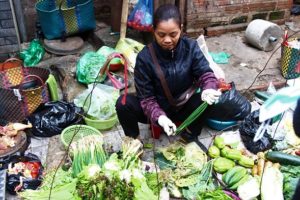 ハノイ旧市街のドンスアン市場裏のカオタン通りで野菜を加工しながら販売するベトナム人女性の写真