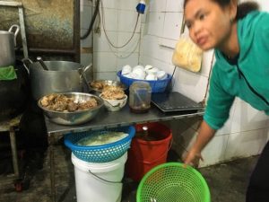フエの食堂に準備されているキノコや牛骨などの食材と、そこで働いているベトナム人の女性の写真。