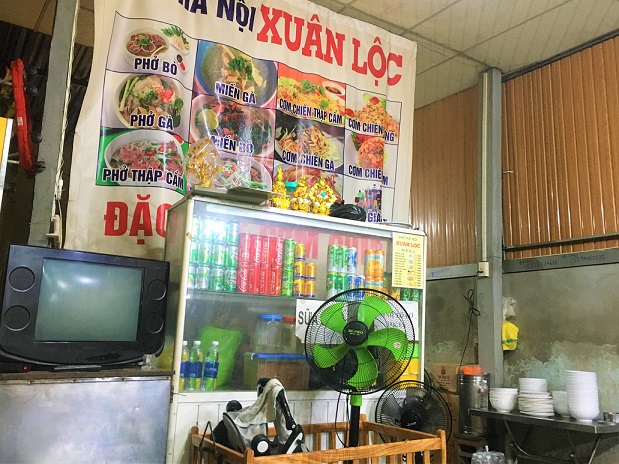 フエのベトナムＢ級グルメ食堂の店内の写真｜テレビやメニュー表、食器や飲み物類がある
