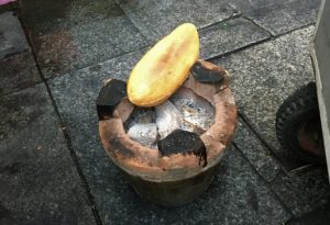 ニャチャンの屋台のおばちゃんがフランスパンを燃える炭の入った火鉢で温めてからバインミーに調理している写真