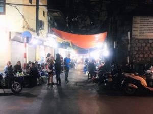ハノイのロンビエン駅の石垣の下の屋台で食事をするベトナムの人々の写真
