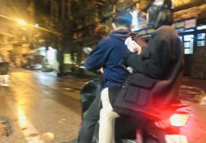 コンビニでビールを買ってバイクに二人乗りしてアパートに帰るベトナムのカップルの写真