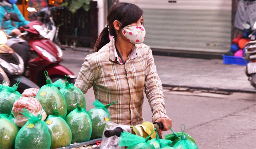 ハノイの路上で自転車で果物を売り歩くベトナム人女性の写真